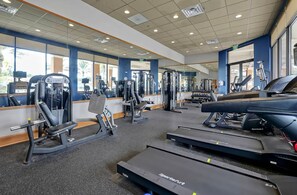 A gym with cardio equipment, weight machines, and mirrors on the walls. - 4BR Townhouse at Regal Oaks (Kissimmee)