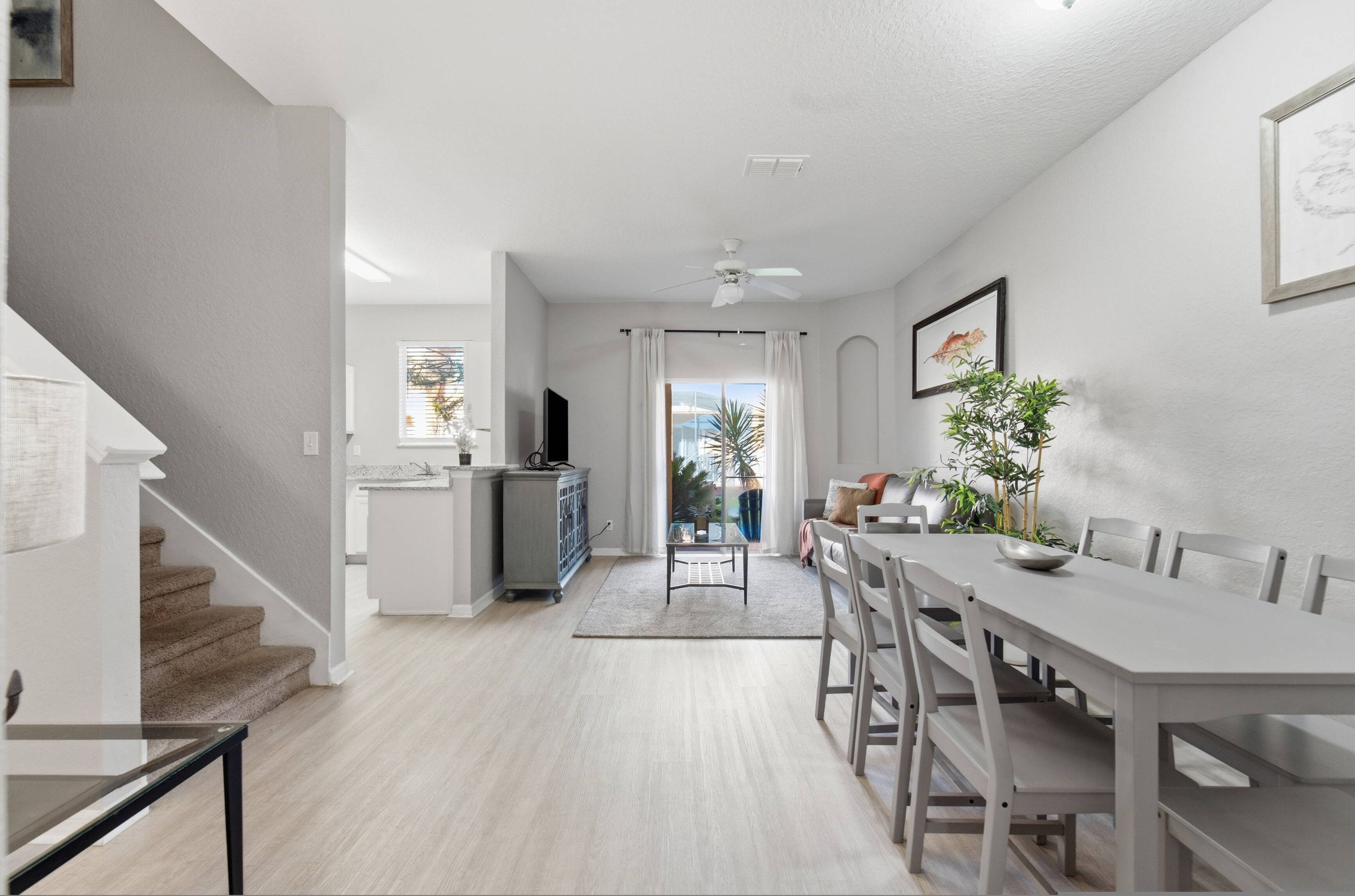 A modern kitchen with a dining area, a staircase, and a view of the outdoors.