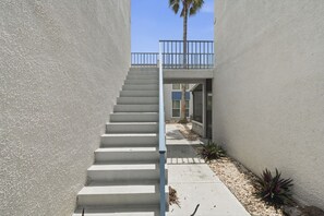 A concrete staircase leading to a balcony with a metal railing. - Modern 2BR Condo in a Prime Walkable Location (Madeira Beach)