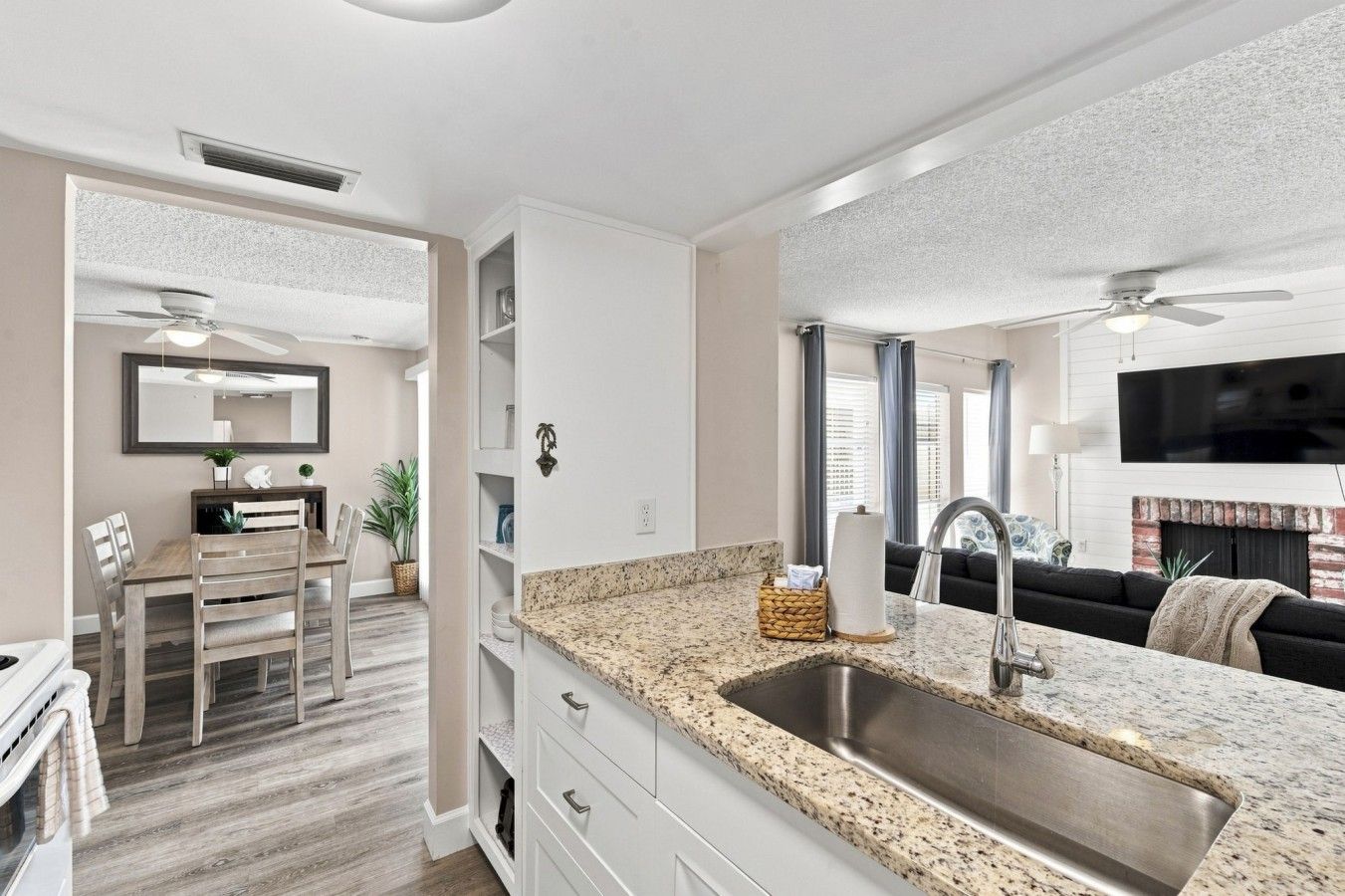 A modern kitchen with granite countertops, a stainless steel sink, and a dining area with a wooden table and chairs.