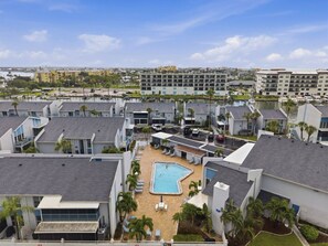 Een resort met een centraal gelegen zwembad, meerdere gastenkamers en een jachthaven op de achtergrond.