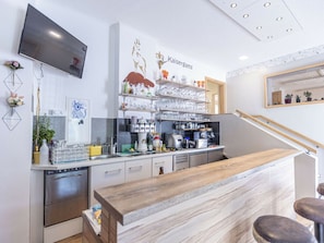A modern kitchen with a wooden counter, stainless steel appliances, and a mounted television. - Comfort Plus Holiday Apartment III (Eisenerz)