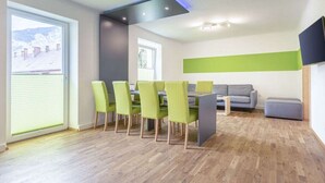 Un salon moderne comprenant un coin repas, un canapé gris et un téléviseur à écran plat fixé au mur.