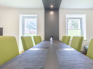A conference room with a long table and chairs, large windows, and a ceiling light. - Comfort Plus Holiday Apartment III (Eisenerz)
