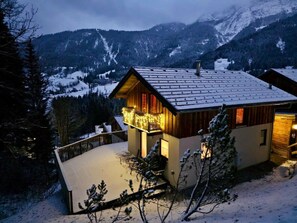 Ein Chalet mit Balkon, Holzhülle und Blick auf schneebedeckte Berge.