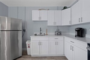Eine moderne Küche mit weißen Schränken, einem Edelstahlkühlschrank, einer Kaffeemaschine und einem Toaster.