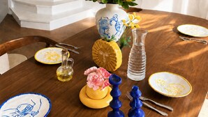 A dining table set with plates, a vase with yellow flowers, a pitcher, and a decorative bowl. - 360° Rooftop, Paris Monuments & Eiffel View from Bed - Artist’s Apt (Paris)