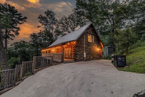 A log cabin with a porch, a metal roof, and a gravel driveway. - Bear Bungalow | Mtn & Forest Views | Hot Tub (Sevierville)