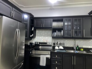 A modern kitchen with stainless steel appliances, dark cabinetry, and a tiled backsplash. - 
Welcome Home !! to a stylish 2 bed, 2.5 bath apartment on UpperWaterloo Road (Kingston)