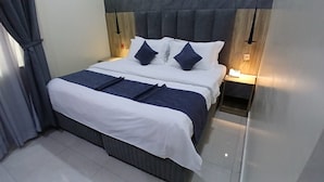Una habitación de hotel con una cama, mesitas de noche y una mesilla.