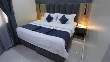 Quarto de hotel com cama, mesas de cabeceira e um criado-mudo.