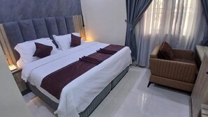 Una habitación de hotel con una cama grande, un sofá y una ventana con cortinas.