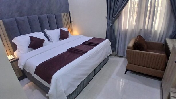 Una habitación de hotel con una cama grande, un sofá y una ventana con cortinas.