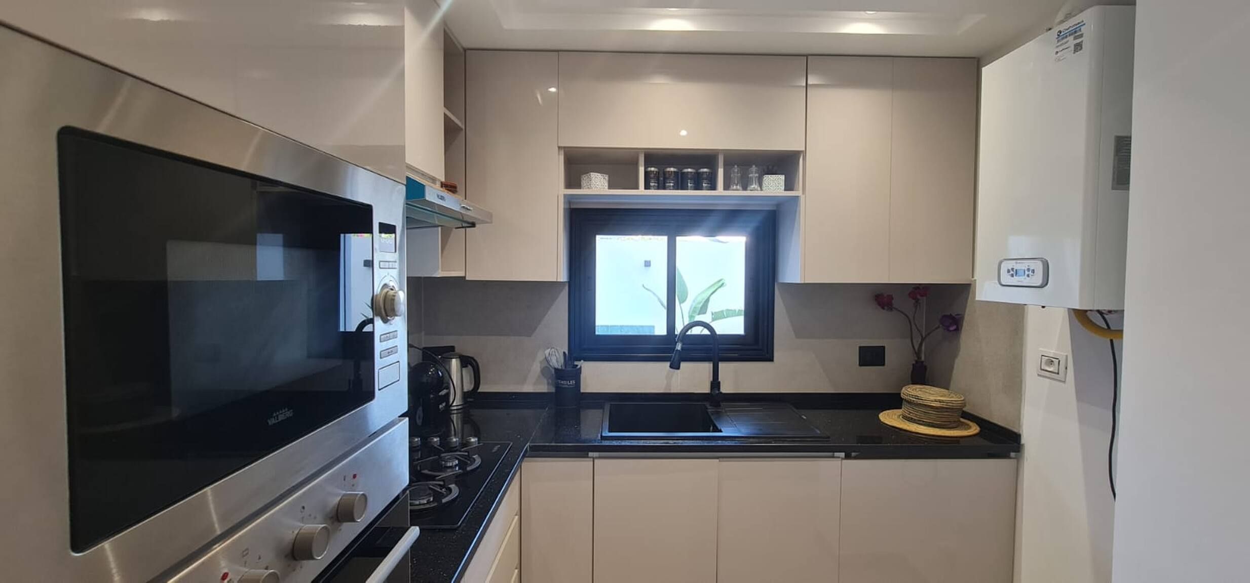 A compact kitchen with a built-in oven, a stove, and a window above the sink.