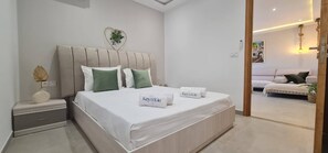 Un dormitorio moderno con una cama, mesitas de noche y vistas a otra habitación.