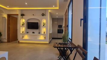 A modern interior with a central TV, recessed lighting, and a dining area with a bench.