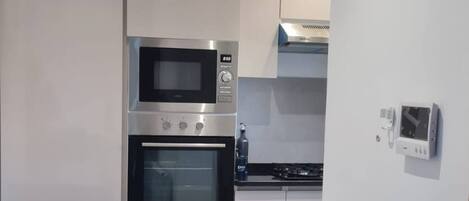 A modern kitchen with a built-in oven, microwave, and a gas stove.