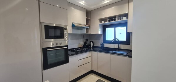Cozinha compacta equipada com micro-ondas, forno e fogão a gás.