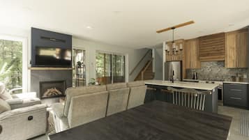 A modern kitchen with a central island, built-in appliances, and a dining area with a dark wood table.