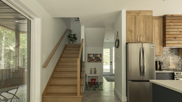 Une cuisine moderne avec un réfrigérateur en acier inoxydable, des armoires en bois et un plancher en béton.