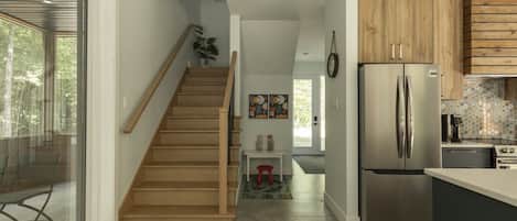 A modern kitchen with a stainless steel refrigerator, wooden cabinets, and a concrete floor.