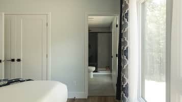 A bedroom with a bed, a door, and a window with curtains.