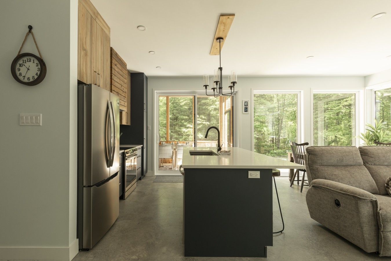 A modern kitchen with a central island, stainless steel appliances, and a view of the outdoors.