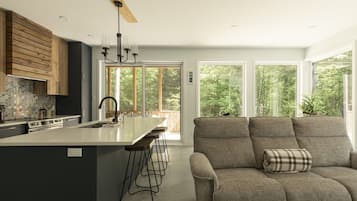 A modern kitchen with a central island, bar stools, and a built-in oven.