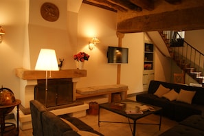 A cozy living room with a fireplace, a sofa, a coffee table, and a television. - Historic House in the Heart of Sancerre – Wines, Restaurants, and the Village Within Walking Distance (Sancerre)