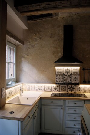 Una cocina con un lavamanos doble, armarios blancos y azulejos decorativos en la pared.