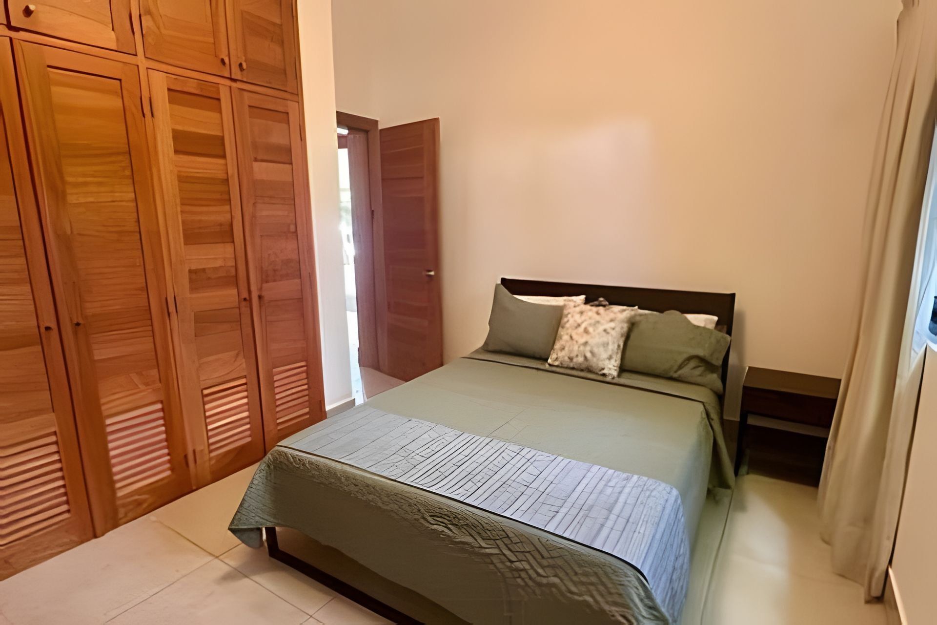 Ein Schlafzimmer mit einem Bett, einem Holzschrank und einer Tür zu einem anderen Raum.
