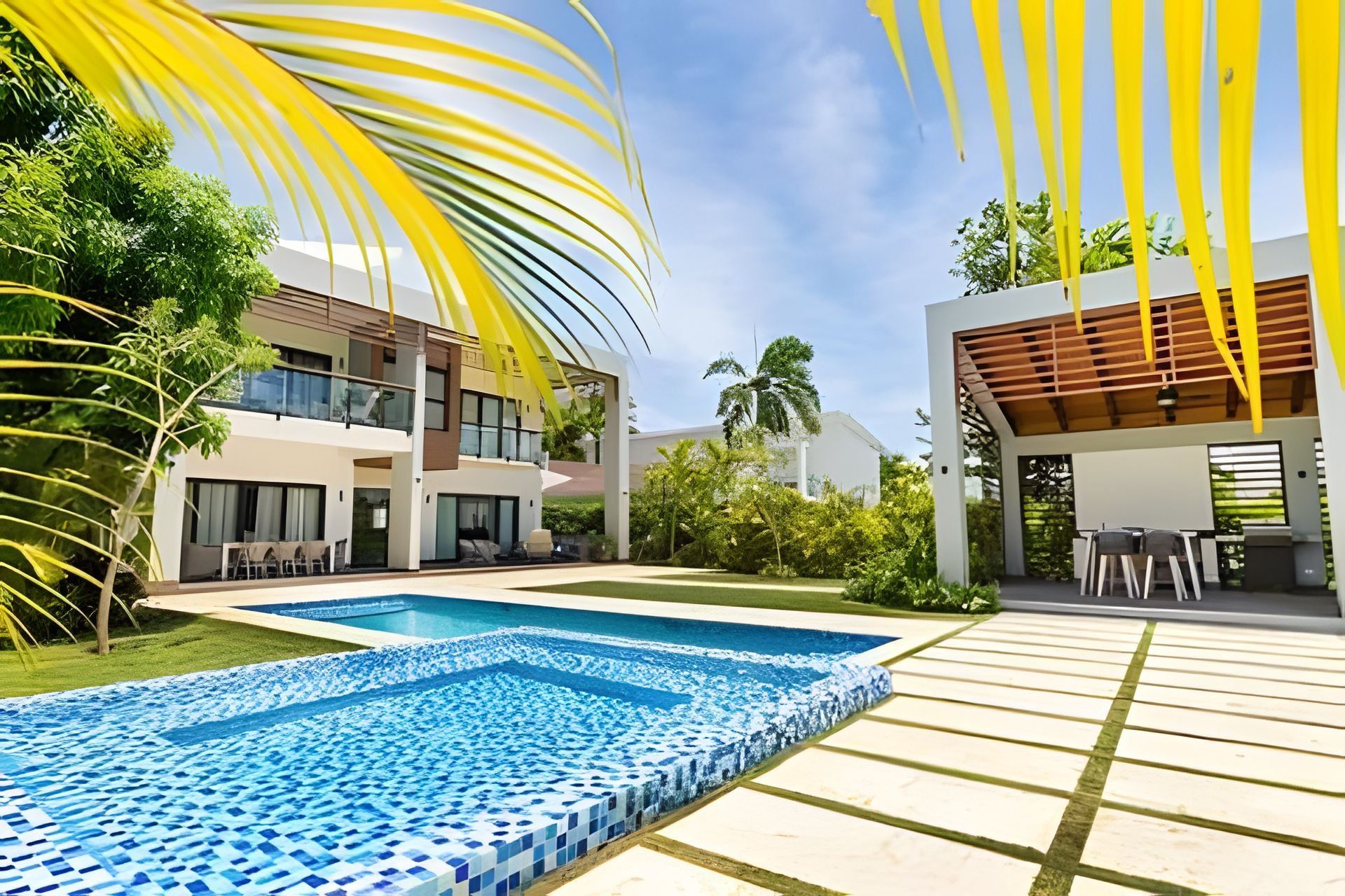Ein modernes Wohnhaus mit Schwimmbad, Sitzgelegenheiten im Freien und üppiger Bepflanzung.