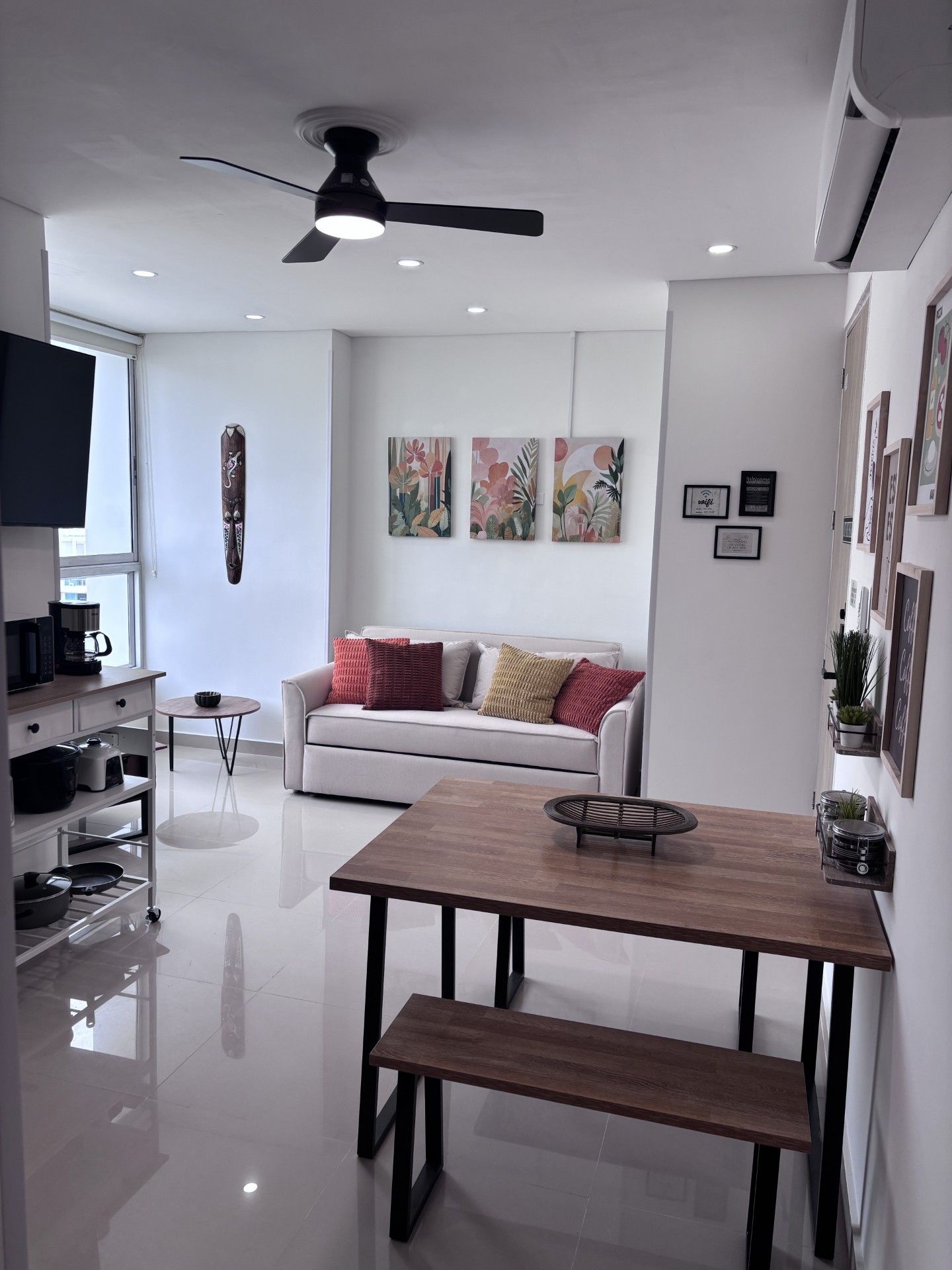 Ein modernes Wohnzimmer mit einem weißen Sofa, einem Holzespeisetisch und einem Deckenventilator.