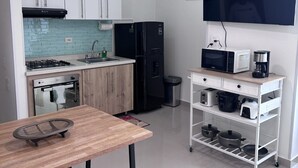 Eine kompakte Küche mit Essbereich, Deckenventilator, Flachbildfernseher und Kaffeemaschine.