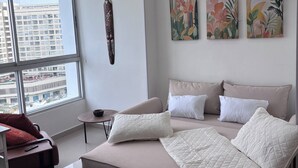 Ein modernes Schlafzimmer mit einem großen Bett, Blick auf die Stadt und zwei an der Wand befestigten Kunstwerken.