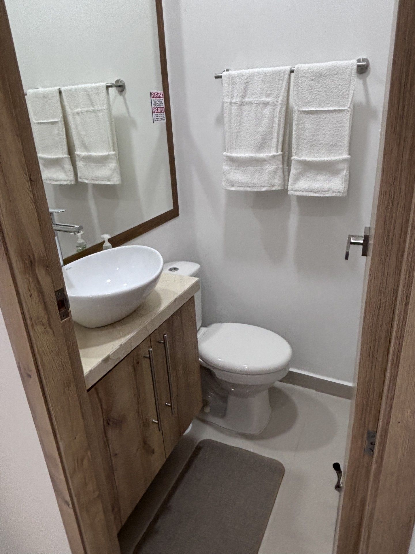 A small bathroom with a sink, toilet, and a mirror. There are two towels hanging on a rack.
