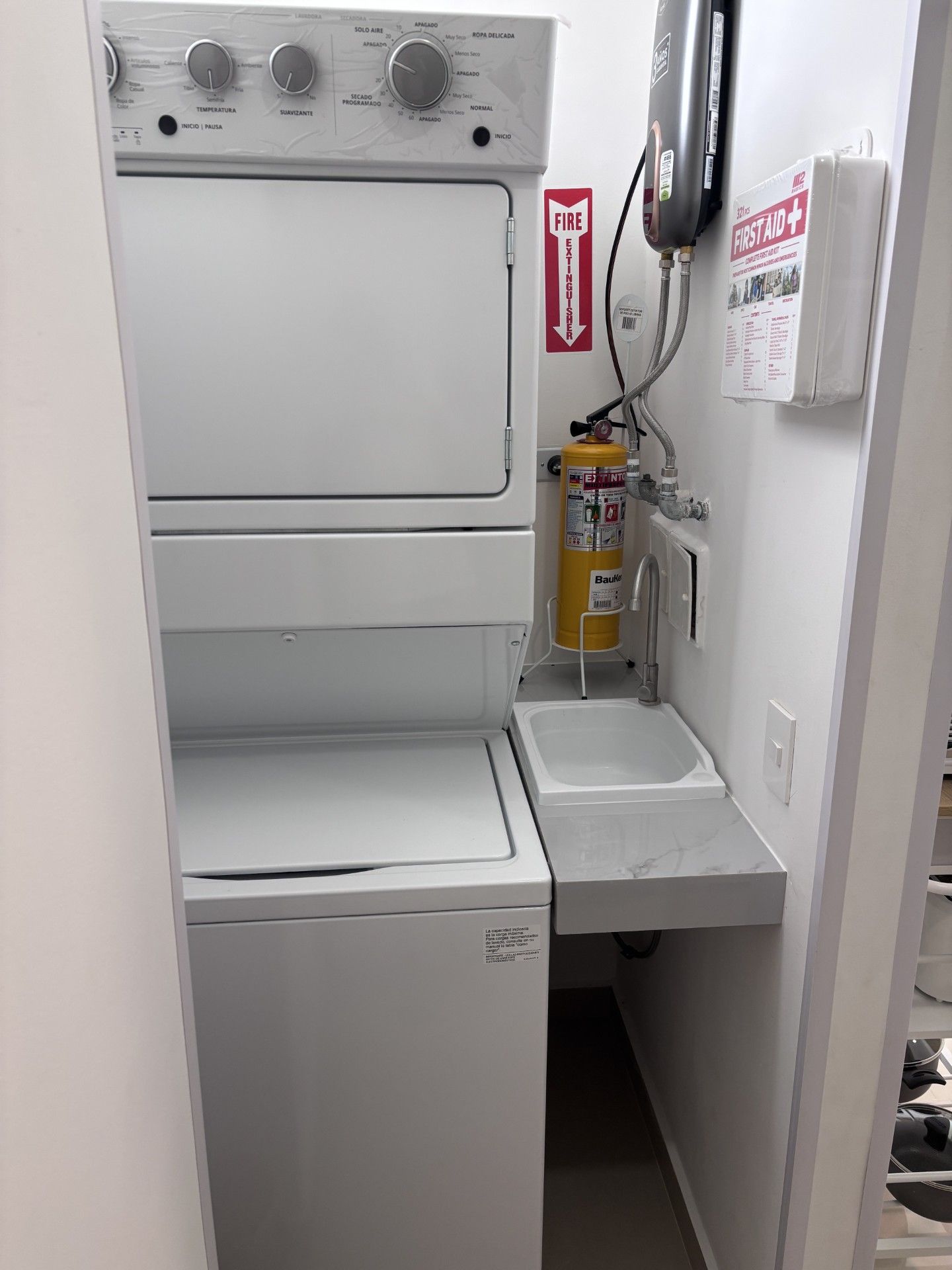 A compact laundry room with a washing machine, a dryer, a sink, and a fire extinguisher.