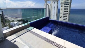 Ein Pool auf dem Dach mit Blick auf den Ozean und hohe Gebäude.