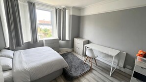 A bedroom with a bed, a desk, and a radiator. - South East London 5-bed House, Sleeps 7 Foresthill (London)