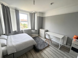 Een slaapkamer met een bed, een bureau en een radiator.