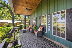 A covered porch with outdoor seating, a welcome sign, and a view of the surrounding landscape.