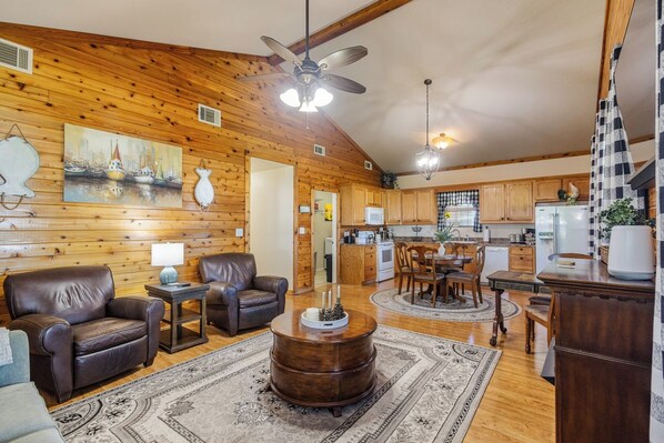 A cabin interior with a living room, dining area, and kitchen.