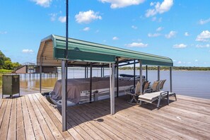 A covered outdoor area with a boat, lounge chairs, and a covered seating area.