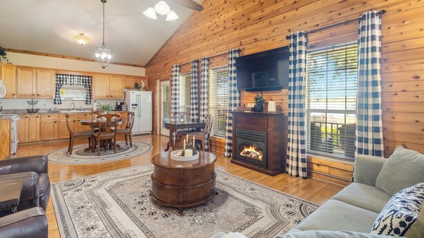 A cozy cabin interior with a dining area, a fireplace, and a living room with a sofa. - HunnyBear Hideout on Cedar Creek Lake (Eustace)