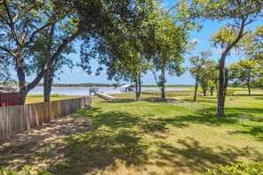 A park with a wooden fence, picnic tables, and a view of a lake.
