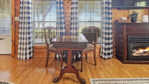 A wooden interior with a checkered table, chairs, a fireplace, and curtains. - HunnyBear Hideout on Cedar Creek Lake (Eustace)