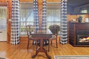 A wooden interior with a checkered table, chairs, a fireplace, and curtains. - HunnyBear Hideout on Cedar Creek Lake (Eustace)