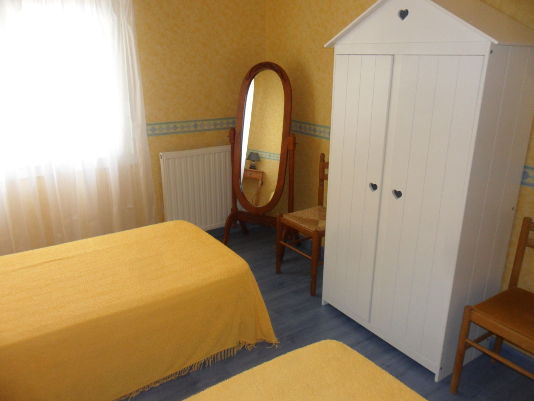 Un dormitorio con dos camas, un armario, un espejo y una silla.