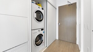 Ett tvättrum med två staplade tvättmaskiner, en trädörr och en ljusströmbrytare på väggen.