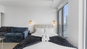 Ett modernt hotellrum med en stor säng, en soffa och utsikt över staden.